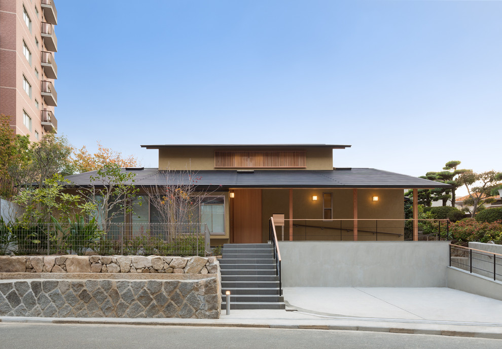 Aménagement d'une façade de maison marron asiatique à un étage avec un toit à deux pans.