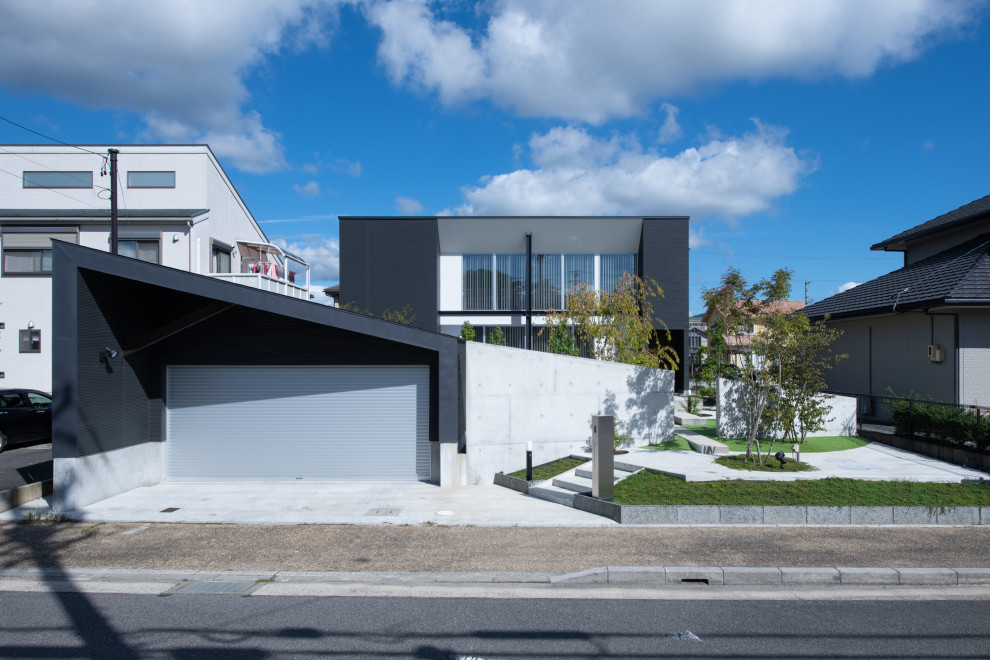 На фото: двухэтажный, черный частный загородный дом в современном стиле с комбинированной облицовкой и односкатной крышей с