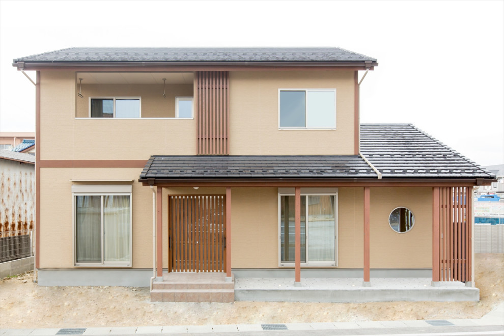 Пример оригинального дизайна: двухэтажный, коричневый частный загородный дом среднего размера в восточном стиле с комбинированной облицовкой, двускатной крышей и черепичной крышей