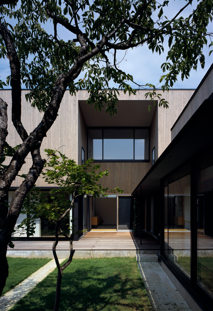 Cette image montre une façade de maison grise minimaliste à un étage avec un toit plat.