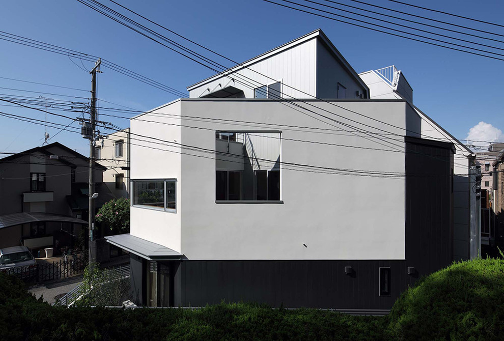Cette photo montre une petite façade de Tiny House blanche moderne en stuc à deux étages et plus avec un toit de Gambrel et un toit en métal.