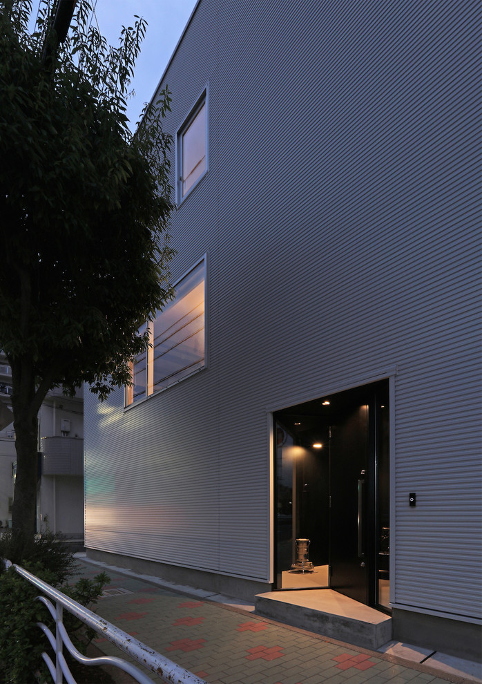 Idée de décoration pour une façade de maison métallique et blanche minimaliste à deux étages et plus avec un toit plat et un toit mixte.
