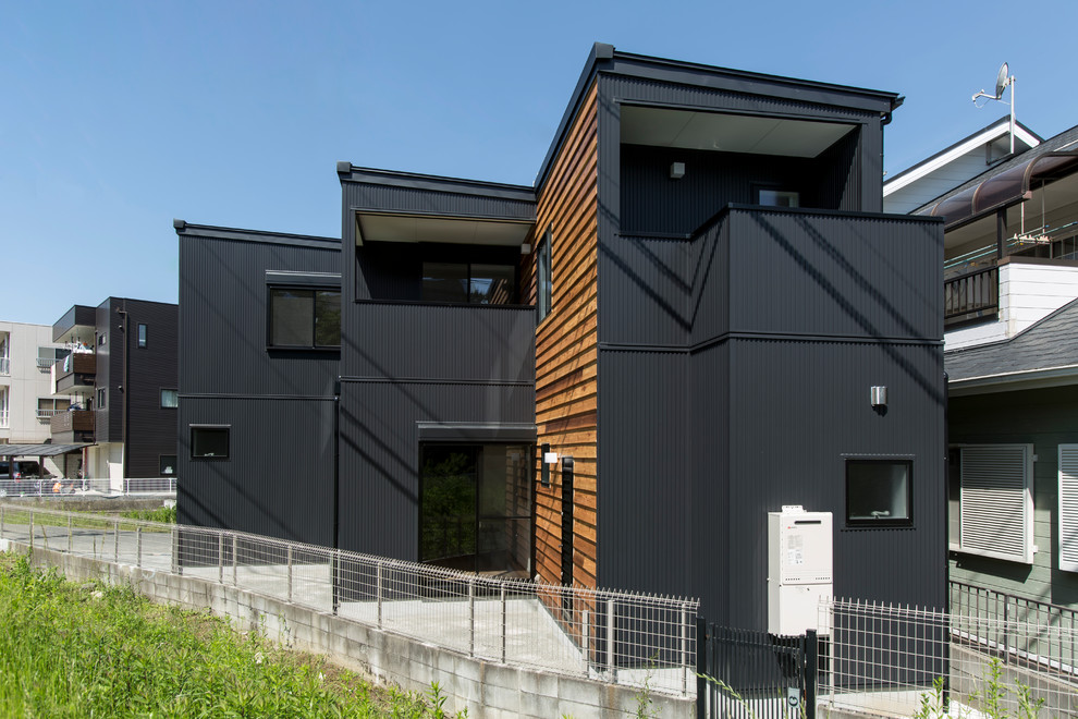 На фото: двухэтажный, черный частный загородный дом среднего размера в стиле модернизм с облицовкой из винила, односкатной крышей и металлической крышей