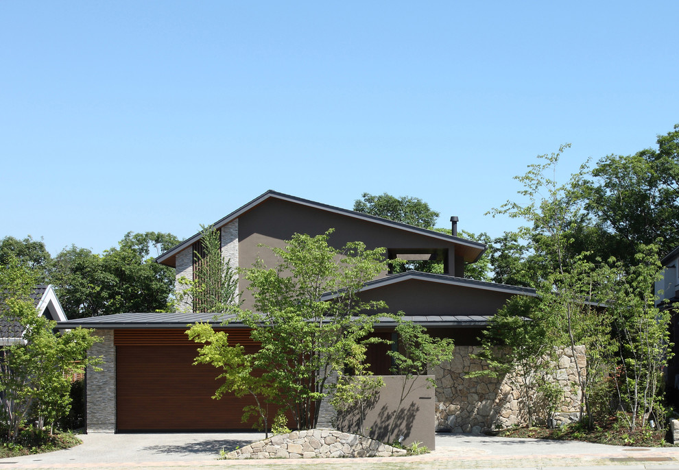 Cette photo montre une grande façade de maison marron moderne en pierre à un étage avec un toit en métal et un toit à deux pans.