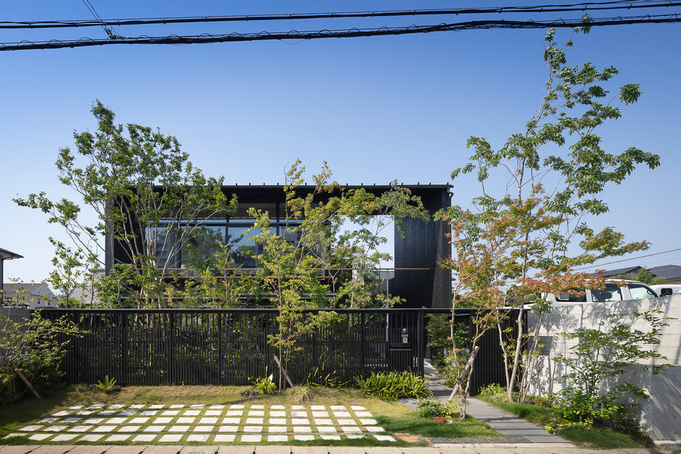 Inspiration pour une façade de maison noire asiatique en bois à un étage avec un toit plat.