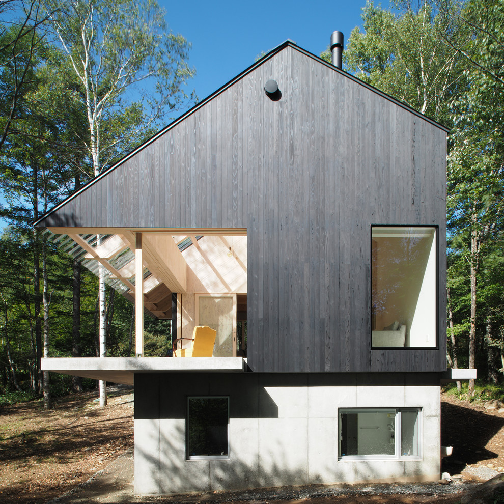 Immagine della facciata di una casa nera contemporanea con rivestimento in legno e tetto a capanna
