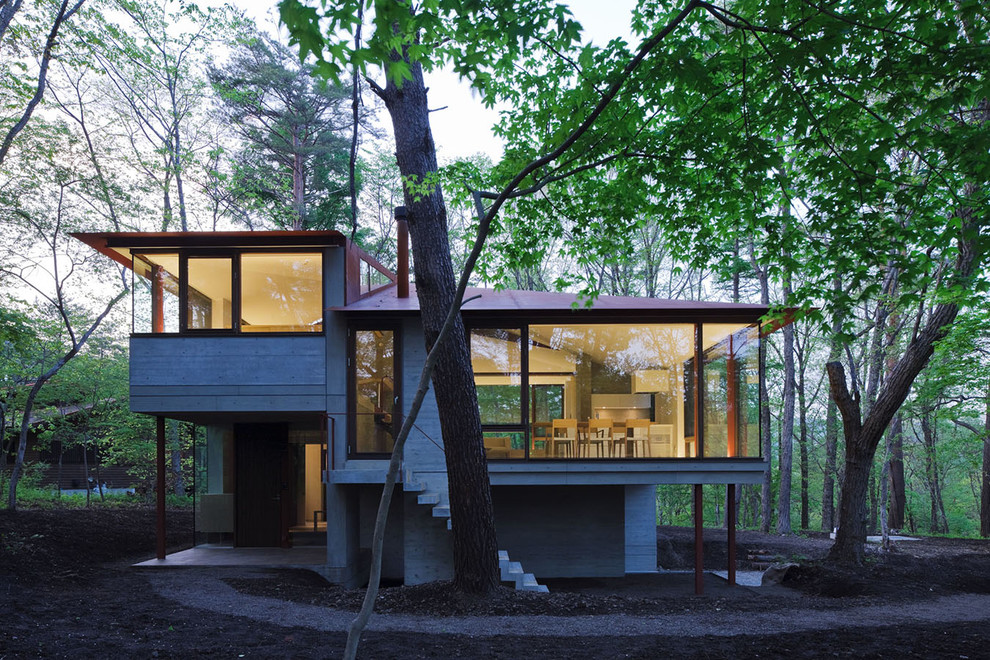 Imagen de fachada de casa gris minimalista grande a niveles con revestimiento de hormigón, tejado a doble faldón y tejado de metal