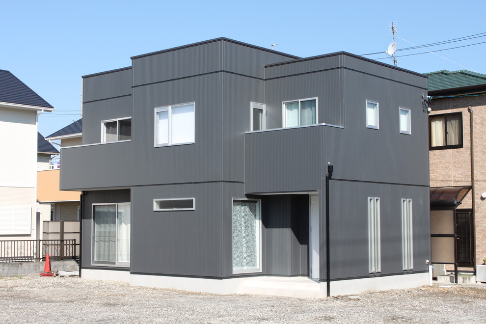 Aménagement d'une façade de maison noire moderne de taille moyenne et à un étage avec un revêtement mixte, un toit plat et un toit en métal.