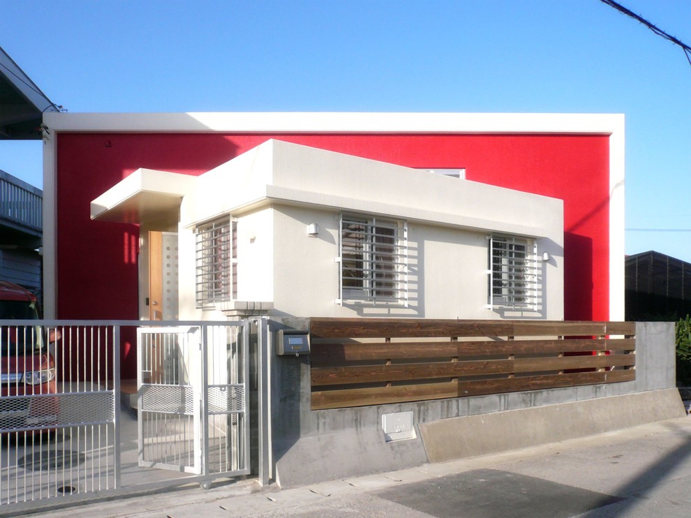 На фото: одноэтажный, красный частный загородный дом в стиле фьюжн с плоской крышей с