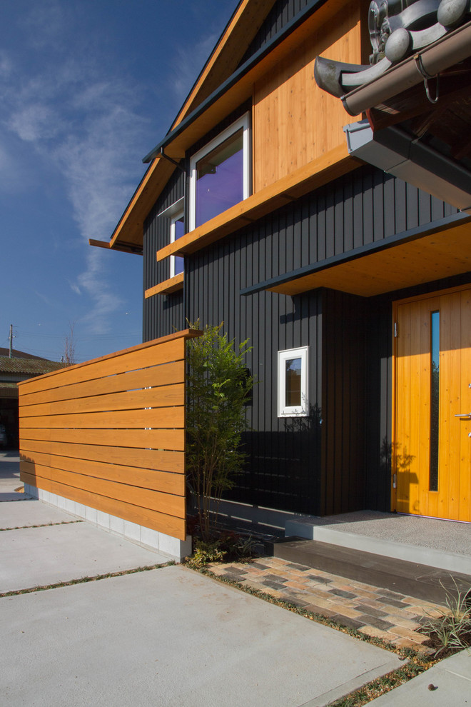 Idée de décoration pour une façade de maison noire minimaliste à un étage avec un toit en appentis et un toit en métal.