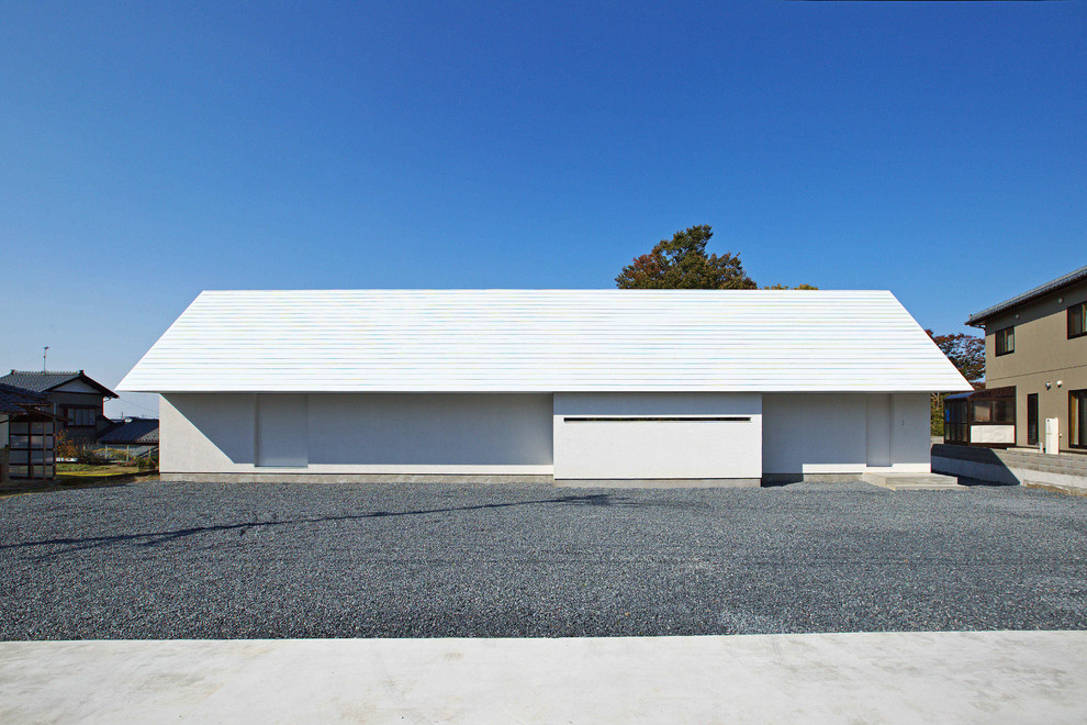 Réalisation d'une façade de maison blanche minimaliste de plain-pied avec un toit à deux pans.