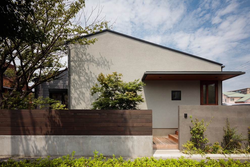 Inspiration pour une façade de maison grise asiatique avec un toit à deux pans.