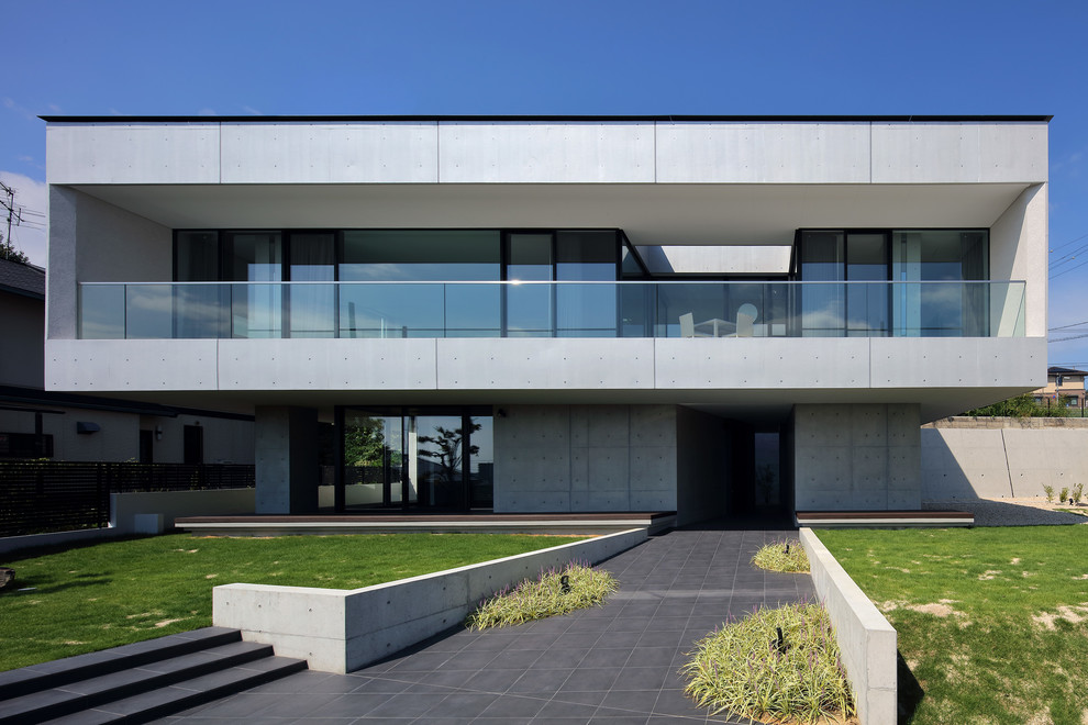 Inspiration pour une façade de maison grise minimaliste en béton avec un toit plat.