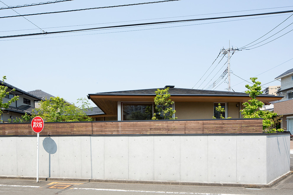 Foto de fachada de casa beige de estilo zen grande de una planta con revestimiento de estuco, tejado a cuatro aguas y tejado de metal