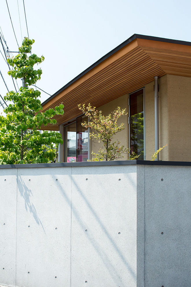 Ejemplo de fachada de casa beige de estilo zen grande de una planta con revestimiento de estuco, tejado a cuatro aguas y tejado de metal