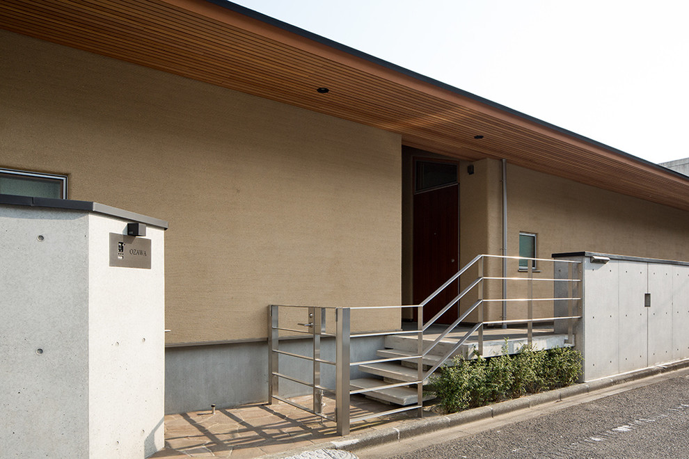 Imagen de fachada de casa beige de estilo zen grande de una planta con revestimiento de estuco, tejado a cuatro aguas y tejado de metal