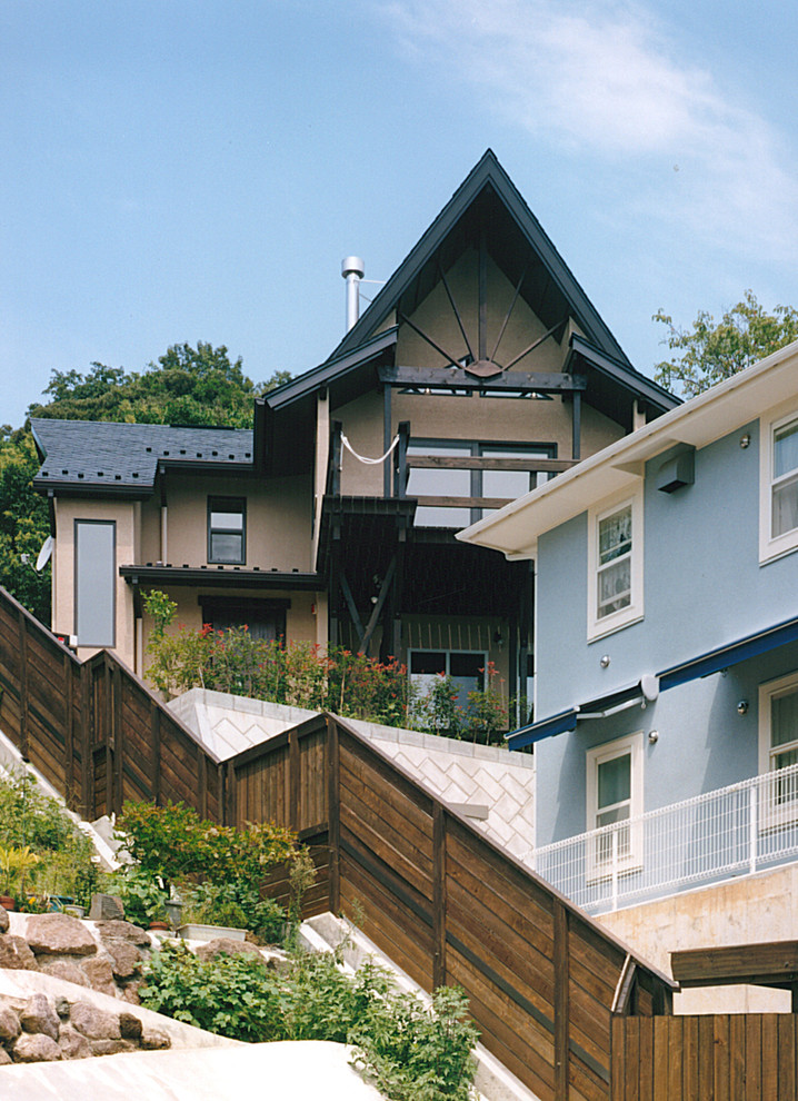 Idée de décoration pour une façade de maison beige asiatique en stuc de taille moyenne et à un étage avec un toit à croupette.
