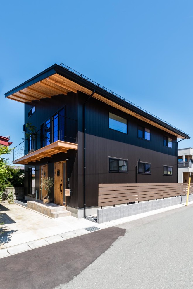 Réalisation d'une grande façade de maison noire asiatique à un étage avec un revêtement mixte, un toit en appentis et un toit en métal.