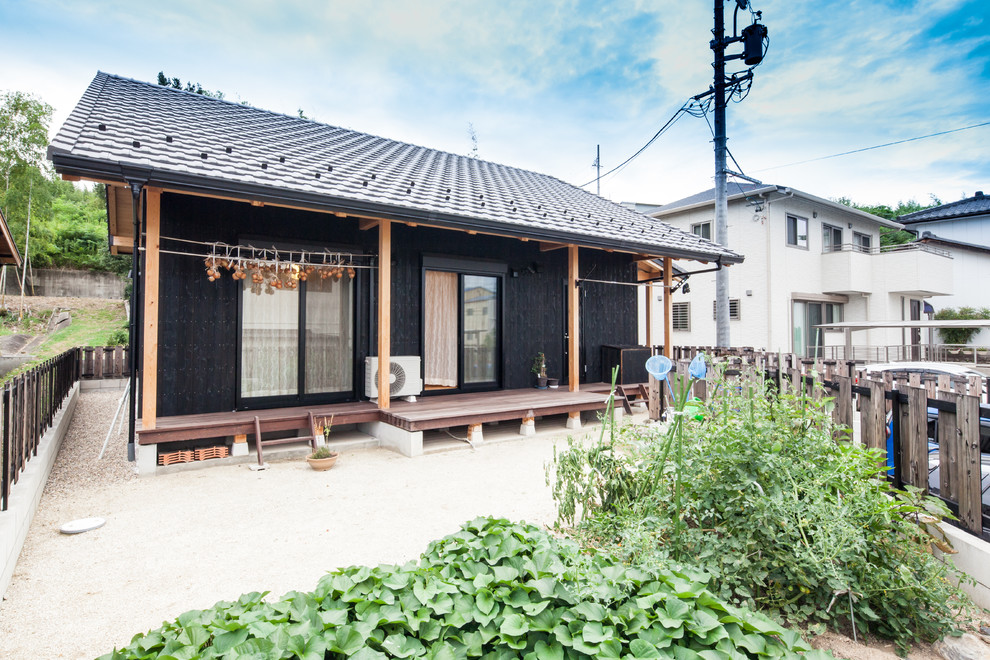 Réalisation d'une façade de maison noire asiatique en bois avec un toit à deux pans et un toit en tuile.
