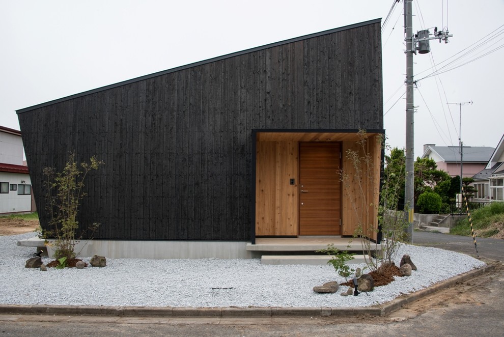 Aménagement d'une façade de maison noire asiatique en bois avec un toit en appentis.