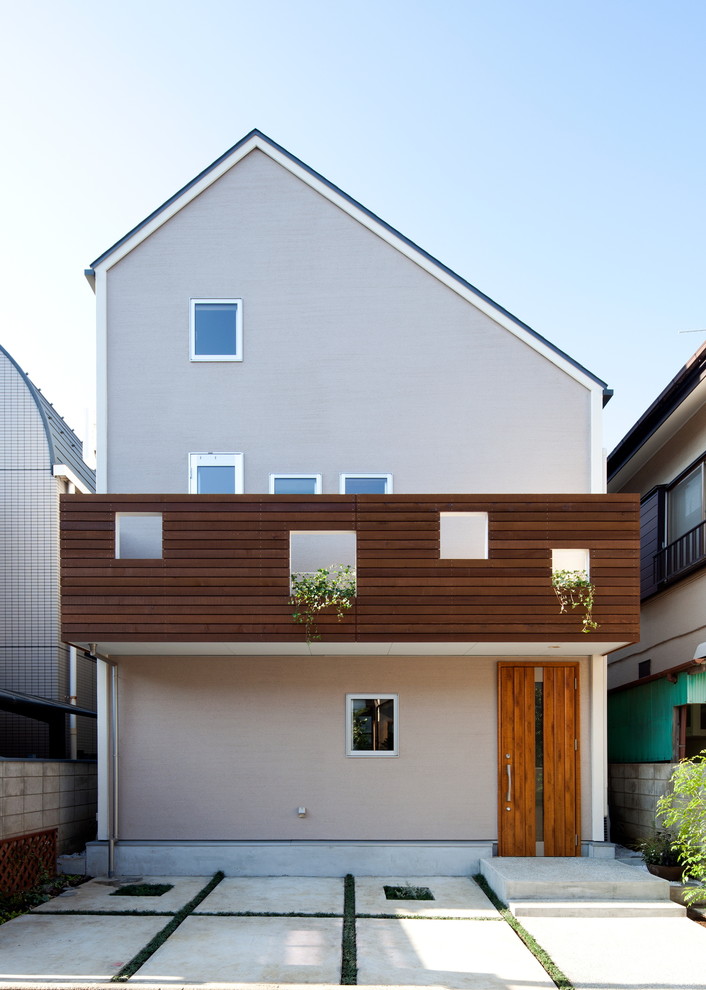 Aménagement d'une façade de maison beige contemporaine en stuc à deux étages et plus avec un toit à deux pans.