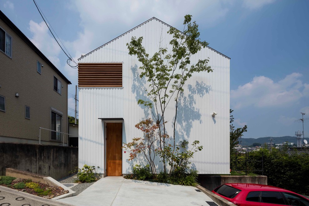 Mittelgroßes, Zweistöckiges Modernes Einfamilienhaus mit Metallfassade, weißer Fassadenfarbe, Satteldach und Blechdach in Osaka