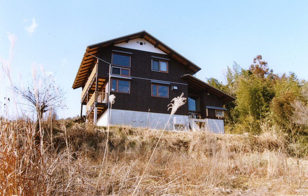 На фото: двухэтажный, деревянный частный загородный дом в восточном стиле с двускатной крышей и металлической крышей