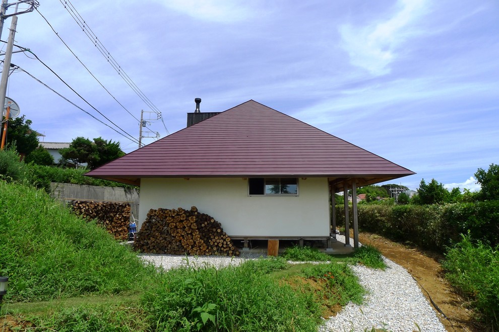 Cette photo montre une grande façade de maison blanche asiatique en stuc de plain-pied avec un toit à croupette et un toit en métal.