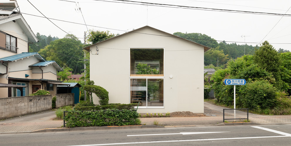 Aménagement d'une petite façade de maison beige asiatique à un étage avec un revêtement mixte, un toit à deux pans et un toit en métal.