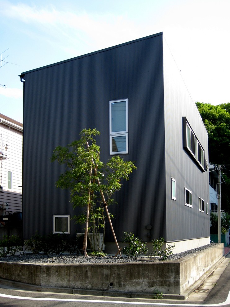 Imagen de fachada de casa negra minimalista de tamaño medio de dos plantas con revestimiento de metal, tejado de un solo tendido y tejado de metal