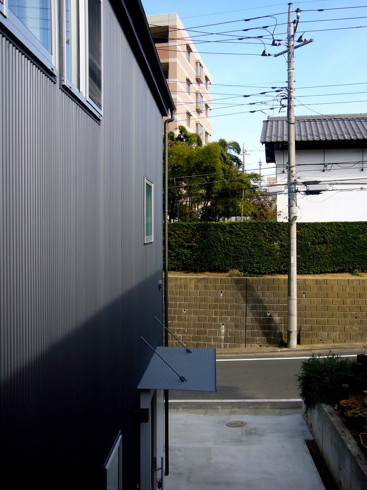 Imagen de fachada de casa negra moderna de tamaño medio de dos plantas con revestimiento de metal, tejado de un solo tendido y tejado de metal