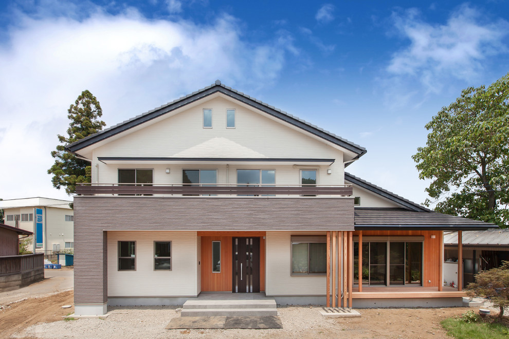 Imagen de fachada de casa beige de estilo zen grande de dos plantas con revestimientos combinados, tejado a dos aguas y tejado de teja de barro