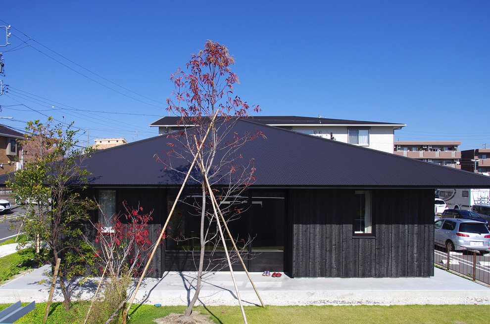 This is an example of a small and black world-inspired bungalow house exterior in Nagoya with wood cladding and a hip roof.