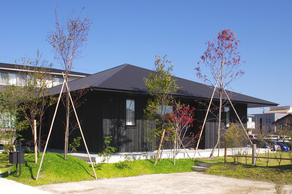 Immagine della facciata di una casa piccola nera etnica a un piano con rivestimento in legno e tetto a padiglione