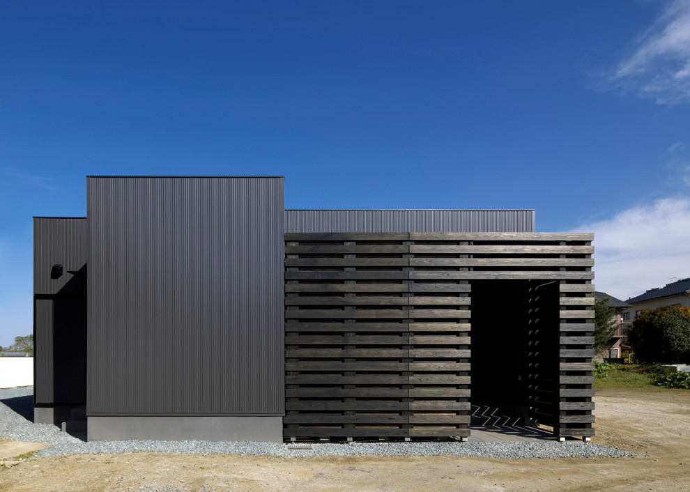 Cette photo montre une façade de maison noire moderne en bois de plain-pied avec un toit plat.