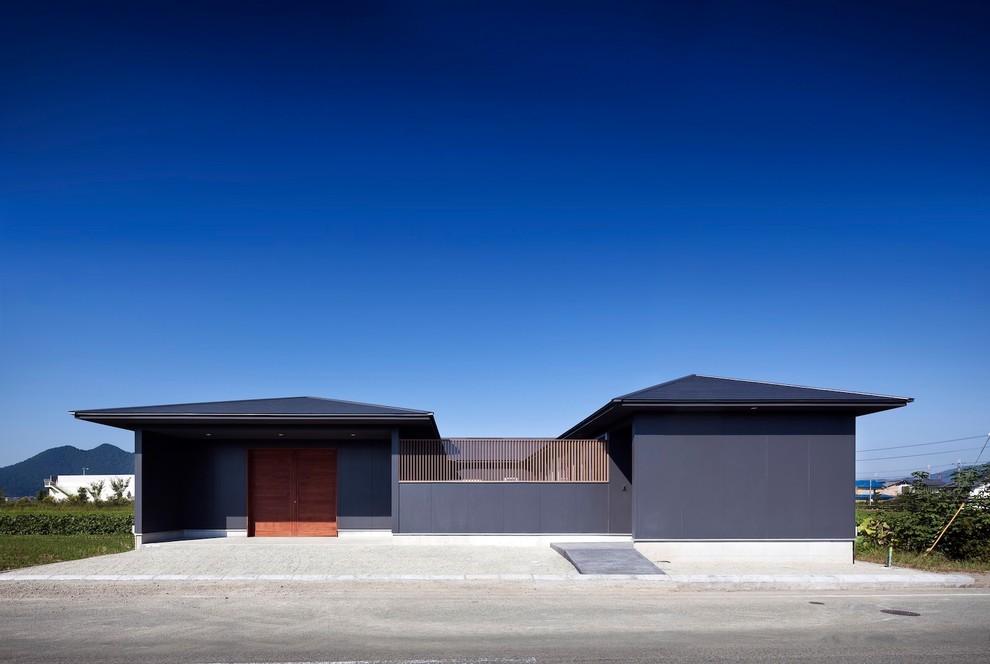 Réalisation d'une façade de maison noire design de plain-pied avec un toit à deux pans.