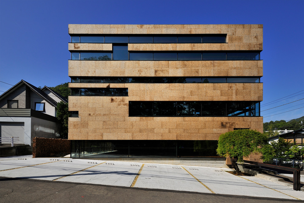 Imagen de fachada marrón moderna de tres plantas con tejado plano