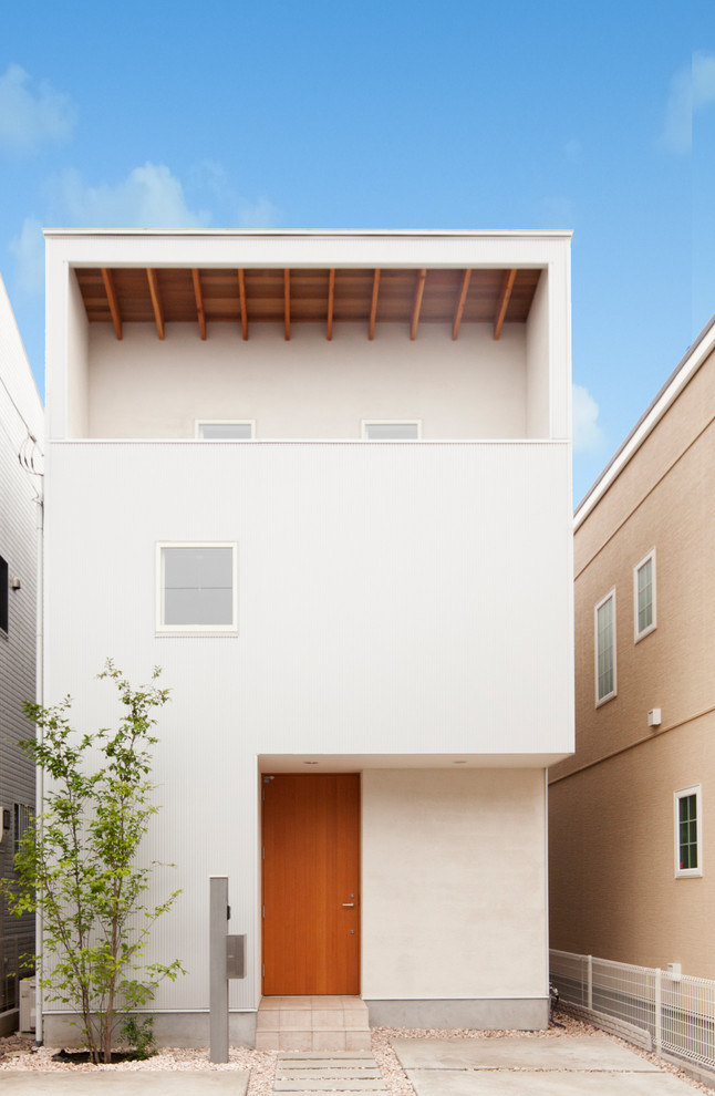 Photo of a white modern render house exterior in Tokyo with three floors and a flat roof.