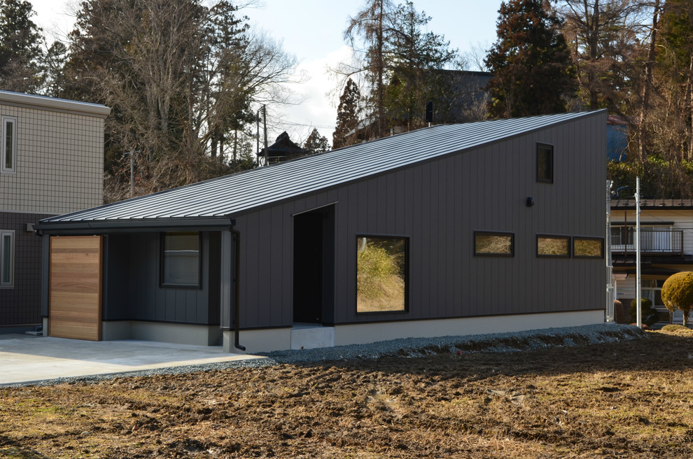 Diseño de fachada de casa negra de estilo americano pequeña de una planta con revestimiento de metal, tejado de un solo tendido y tejado de metal