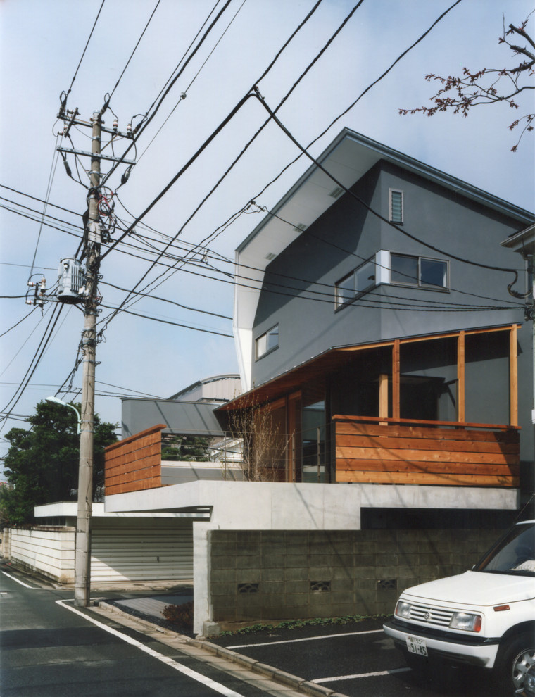 Imagen de fachada de casa gris asiática de tamaño medio de tres plantas con revestimiento de estuco, tejado de un solo tendido y tejado de metal