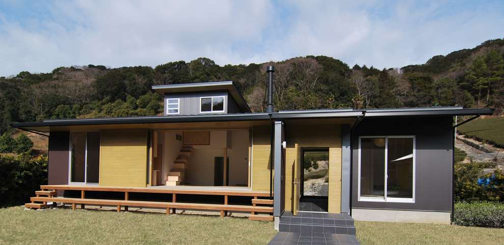 Стильный дизайн: двухэтажный, черный частный загородный дом среднего размера в восточном стиле с облицовкой из металла, односкатной крышей, металлической крышей, коричневой крышей и отделкой доской с нащельником - последний тренд