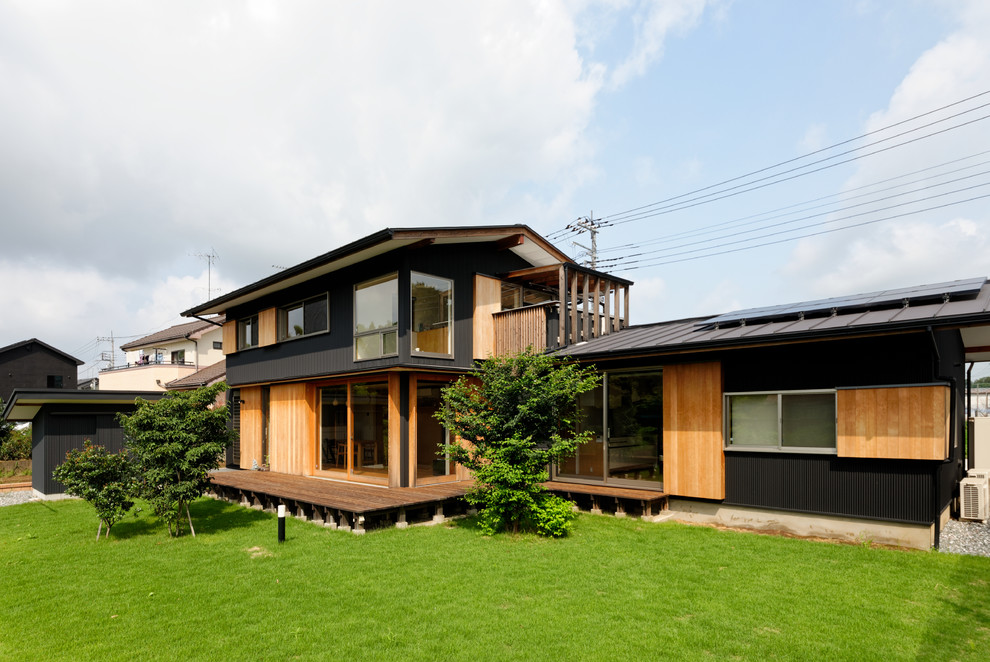 Imagen de fachada de casa negra de estilo zen de dos plantas con tejado a dos aguas y tejado de metal