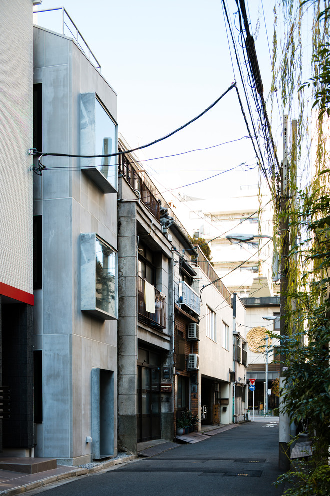 Dreistöckiges, Kleines Modernes Einfamilienhaus mit grauer Fassadenfarbe und Pultdach in Tokio