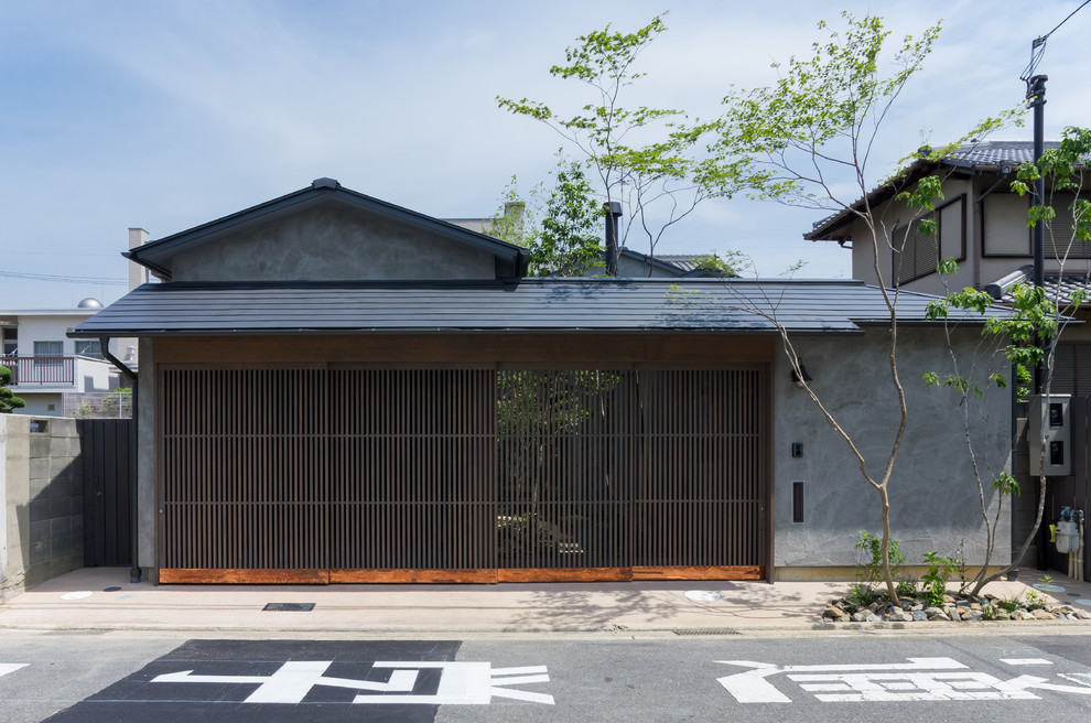 Idée de décoration pour une façade de maison grise asiatique avec un toit à deux pans.