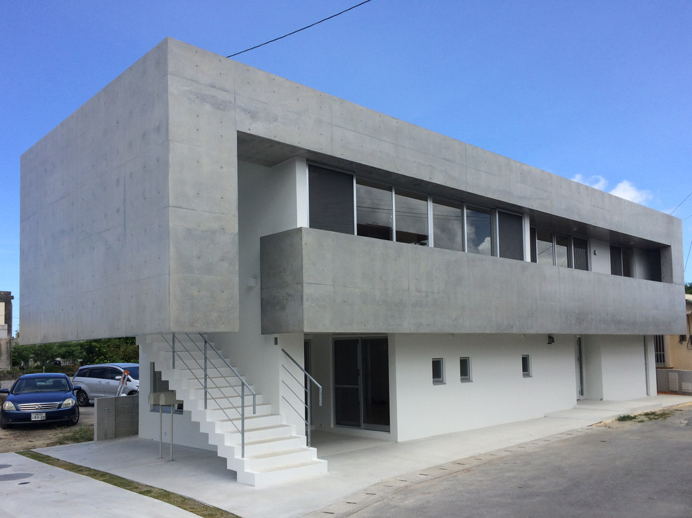 Foto della facciata di una casa bifamiliare grigia moderna a due piani con rivestimento in cemento e tetto piano