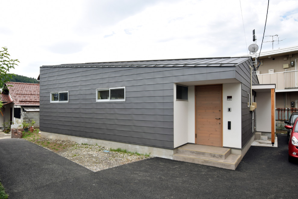 Diseño de fachada de casa gris contemporánea pequeña de una planta con revestimiento de metal, tejado a dos aguas y tejado de metal