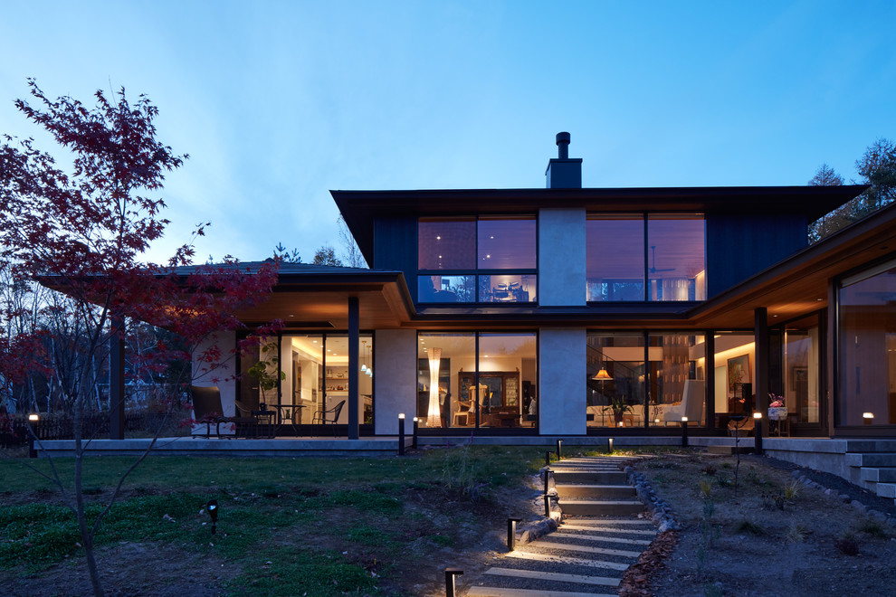 Exemple d'une façade de maison marron tendance en bois à un étage avec un toit plat.
