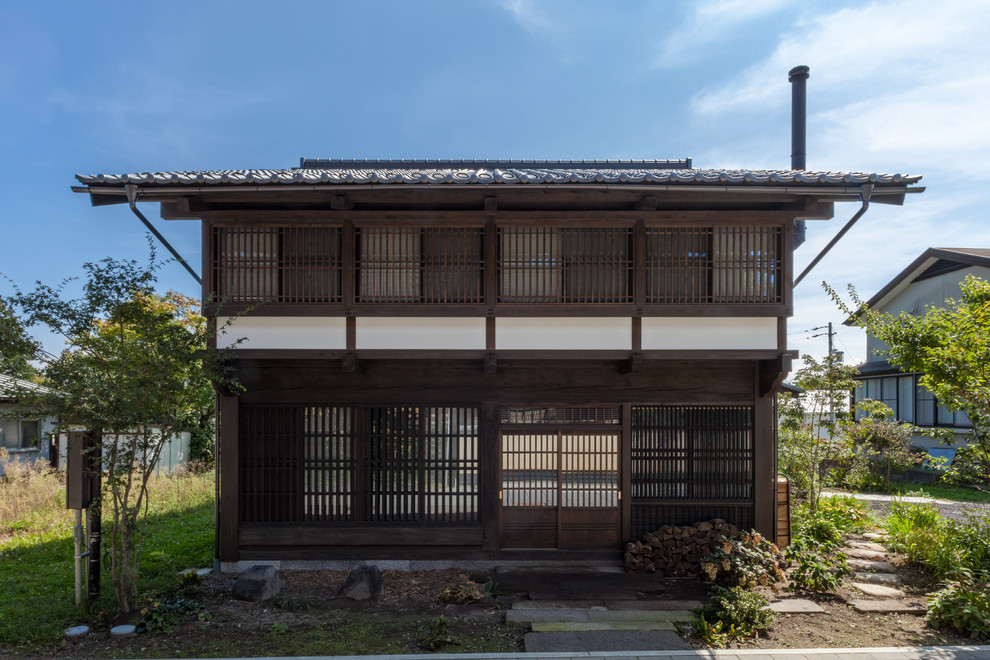 Ejemplo de fachada marrón de estilo zen con revestimiento de madera, tejado a dos aguas y tejado de teja de barro
