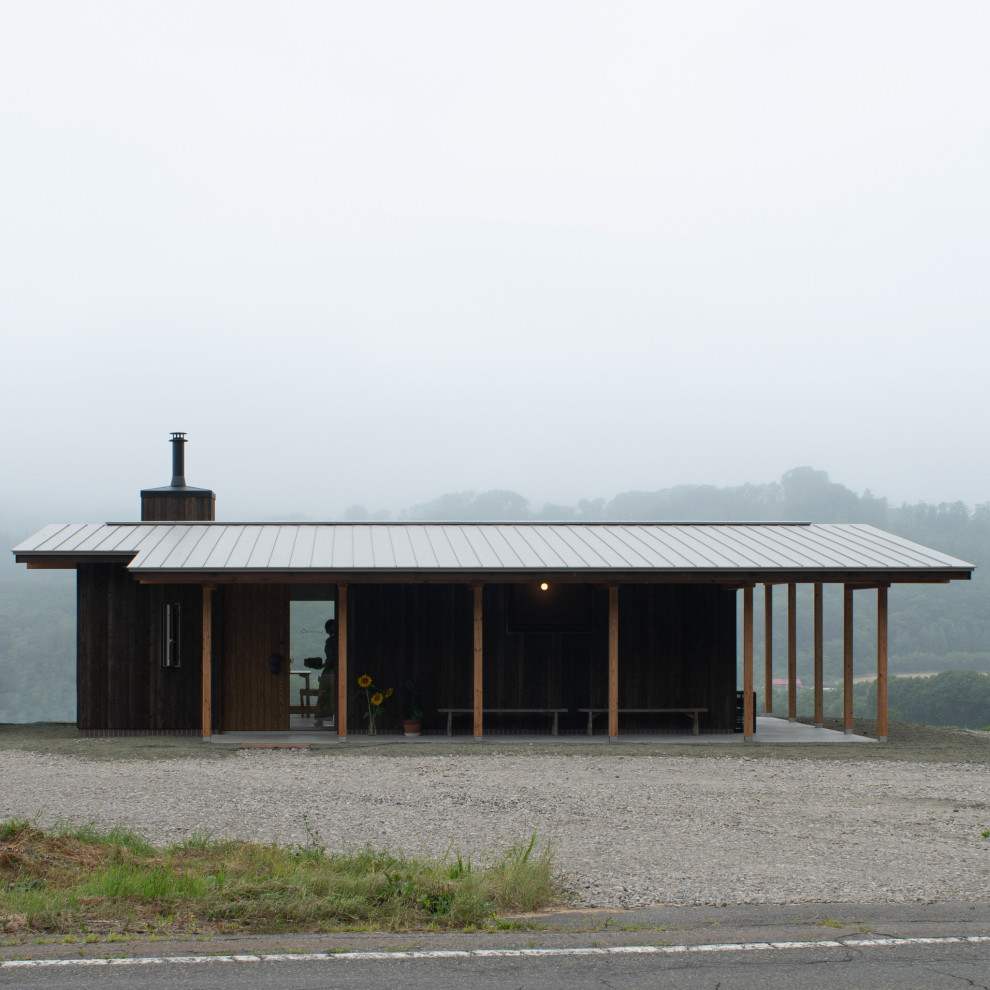 Imagen de fachada de casa negra escandinava pequeña de una planta con revestimiento de madera, tejado a dos aguas y tejado de metal