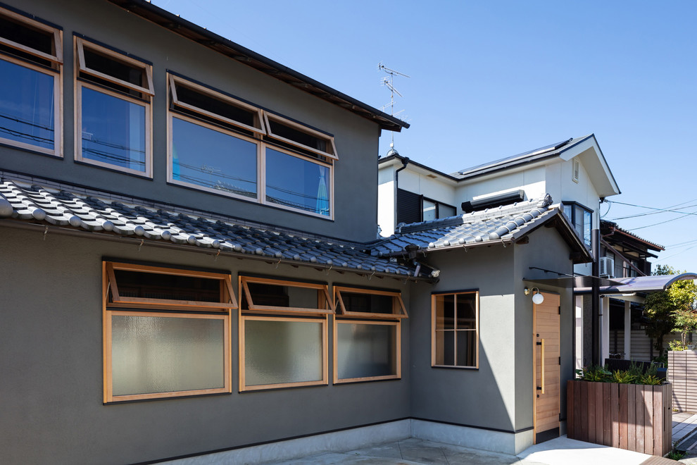 Foto de fachada de casa gris minimalista de tamaño medio de dos plantas con revestimiento de estuco, tejado a dos aguas y tejado de varios materiales